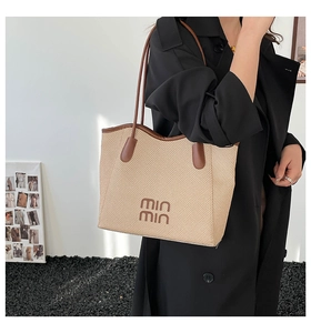 Close-up of a woven tote bag with wavy edges and leather straps worn on the shoulder