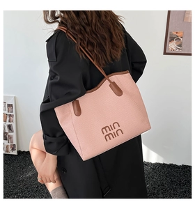 Detail of pink woven tote bag with brown leather straps and min min logo on model