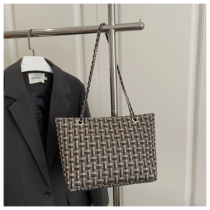Close-up of checkered tweed tote bag texture with elegant metal chain shoulder strap