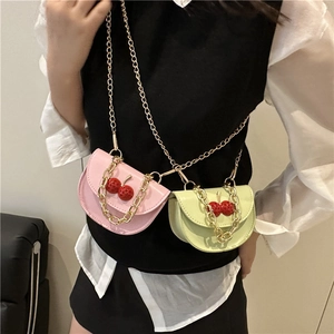 Mini sac bandoulière avec détail cerise et chaîne porté par un mannequin pour le style