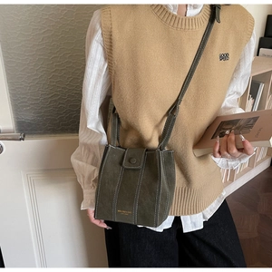 Detail of olive green suede bucket bag with white stitching and branded logo detail