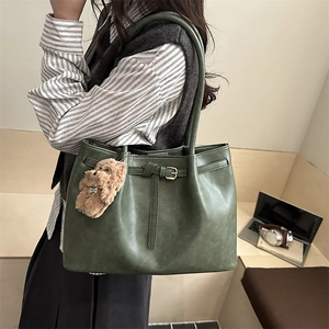 Dark green minimalist faux leather tote bag with buckle detail and plush bear charm