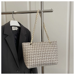 Detail of tweed checkered tote bag with metal chain strap hanging on a blazer