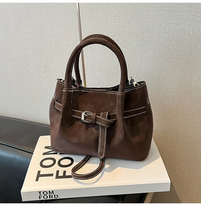 Close-up of dark brown matte texture handbag with contrast stitching and silver buckle