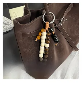 Close-up of ethnic style beaded charm in brown, cream, and yellow on a tote bag
