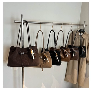 Collection of retro suede tote bags in six colors with beaded charms on a rack