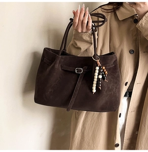 Close-up of brown suede tote bag featuring slim leather straps and wood bead charms