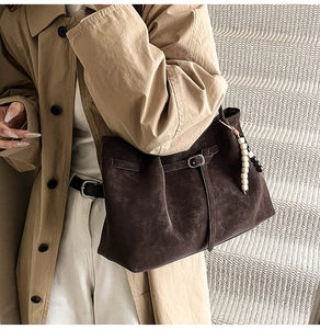 Detail of dark brown suede tote bag with vintage texture and beaded tassel charm