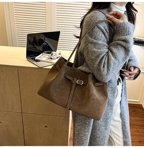 Close-up of brown suede tote bag featuring a vintage buckle and dual thin shoulder straps