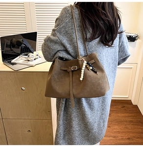 Detail of vintage brown suede tote bag with decorative buckle and beaded pendant