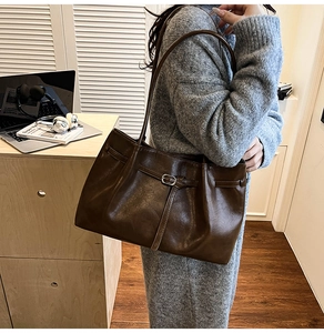 Close-up of deep brown tote bag with pleated texture and stylish metal buckle detail
