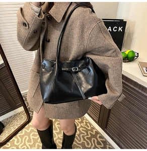 Close-up of glossy black leather tote bag with stylish buckle detail and slim straps