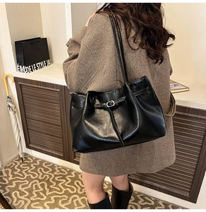 Detail of black glossy leather tote bag with silver buckle and spacious design