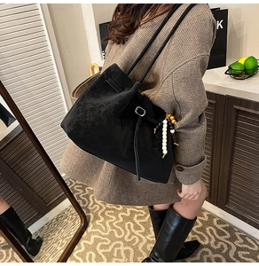 Detailed view of black matte suede tote bag with stylish beaded pendant and silver buckle