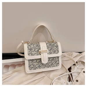 Detail of monogram print on beige leather square handbag with metal clasp and thin strap