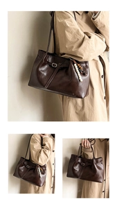 Detail of a dark brown leather tote bag with stylish beaded pendant and strap accents