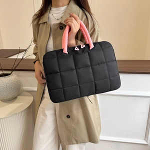 Quilted 14 inch laptop bag with pink handles, shown held by a model in a beige coat