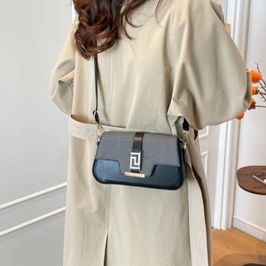 Fashionable grey fabric and black leather crossbody bag with gold buckle on trench coat
