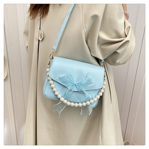 Detailed view of light blue shoulder bag with lace bow and elegant pearl chain
