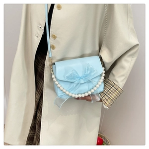 Detail of light blue PU bag with sheer organza bow and decorative pearl chain strap