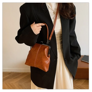Detailed view of brown retro leather shell bag with metal clasp and decorative stitching