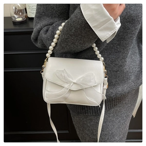 Close-up of white PU leather crossbody bag with mesh bow and pearl chain handle