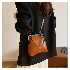 Detail of vintage brown shell crossbody bag with metallic clasp worn by a model