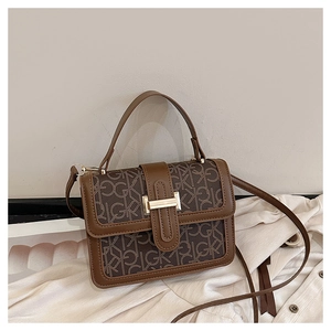 Detail view of the brown GK monogram patterned crossbody bag with metallic buckle closure