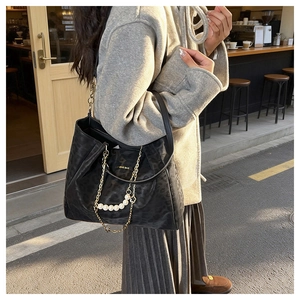 Detail of black leopard tote with pearl chain and floral pendant in a street scene