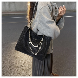 Detail of leopard print tote bag with pearl chain and floral charm in city setting