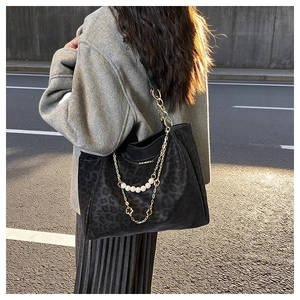 Detail of leopard print tote bag featuring gold chain and pearl strap in evening sunlight