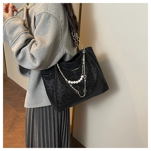 Detailed view of leopard print tote bag with gold chain and pearl floral decoration