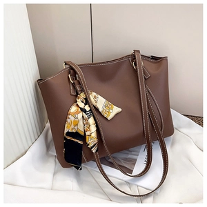 Detail einer braunen Shopper-Tasche mit Kontrastnaht und dekorativem Seidenschal