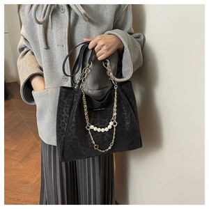 Detail of leopard print tote bag featuring gold chains, pearl charms and suede texture