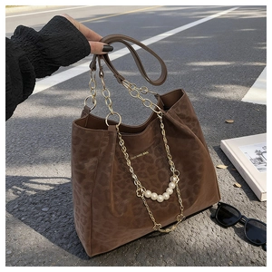 Detail of leopard print tote bag with gold chain, pearl charms and suede texture