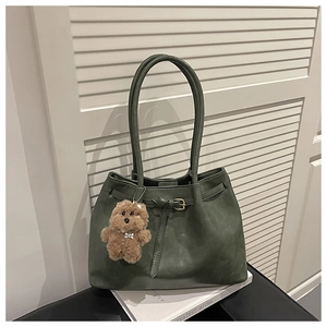 Detail of dark green tote bag with belt buckle accent and cute brown plush puppy charm