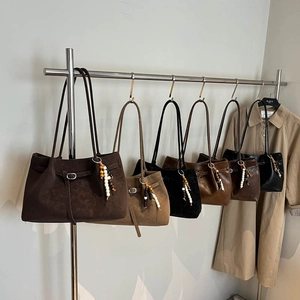 Minimalist matte suede tote bags in various colors on a rack with beaded charm details