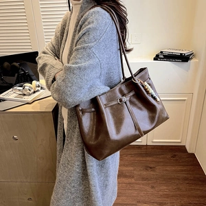 Brown vintage faux leather tote bag with decorative bead charm shown with a model
