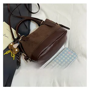 Detailansicht der braunen Wildleder-Patchwork-Tasche mit Bärenanhänger und Goldbeschlägen