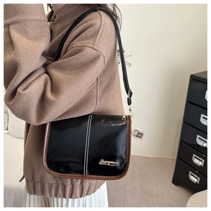 Detail view of a vintage black shoulder bag with white stitching and gold logo accent