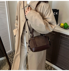 Detail shot of a dark brown crossbody pillow bag worn with a beige trench coat