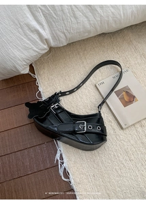 Detail of black glossy leather underarm bag with silver buckles and a bear charm