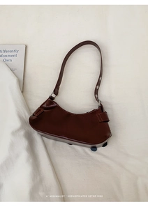 Detail of dark brown shoulder bag featuring metal eyelets and retro minimalist design