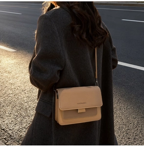 Detail shot of the beige matte PU leather flap bag with wide strap in warm sunset light