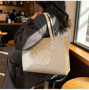 Detailed macro of the vintage cream tote bag featuring embossed M logo and gold rivets
