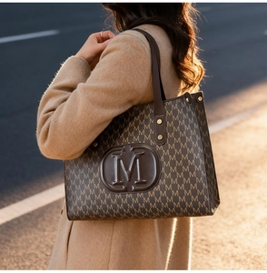 Detail of vintage brown tote bag with M-letter monogram print and metal rivets