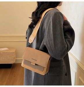Close-up of brown faux leather crossbody bag featuring wide fabric strap and fashion logo