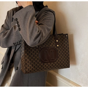 Detail of vintage large tote bag with brown M-pattern and embossed leather shoulder strap