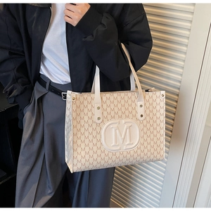 Detail of vintage beige tote bag showing large capacity, M letter print and metal buckles