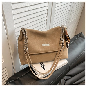 Détail du sac cabas marron clair avec chaîne en métal, texture cuir et breloque en perles